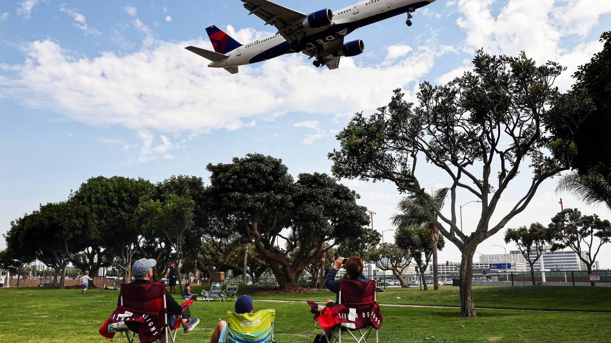 People watch a Delta Air Lines plane land from a park next to Los Angeles International Airport (LAX) in 2021.