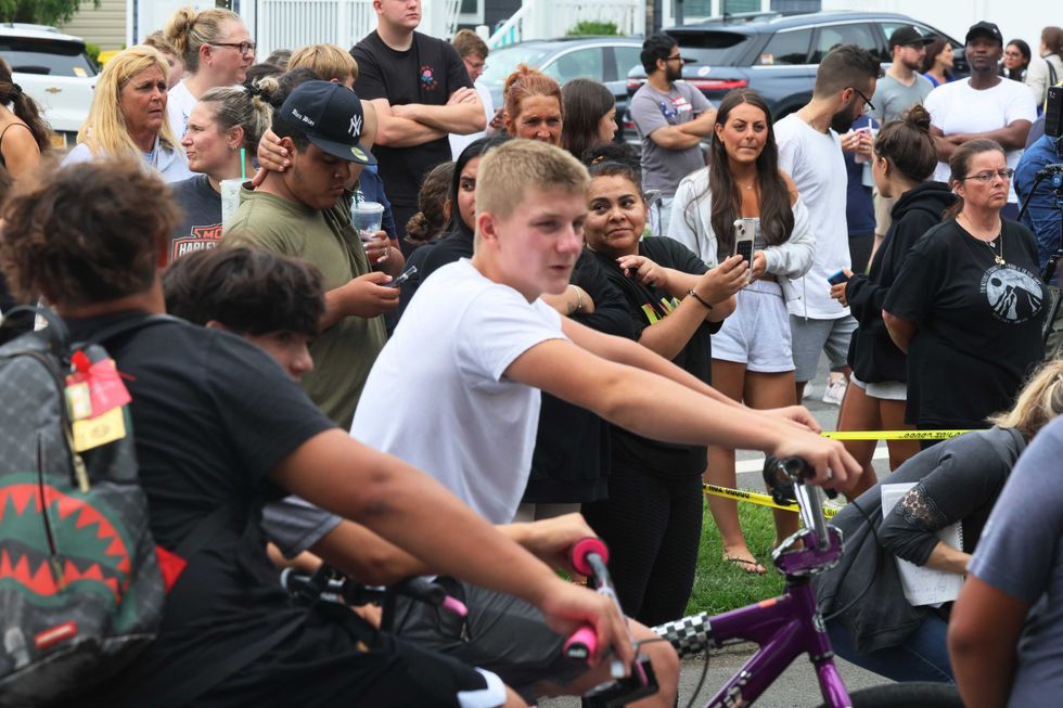 People watch as law enforcement officials investigate the Massapequa Park home of a suspect arrested in the unsolved Gilgo Beach killings on July 14, 2023