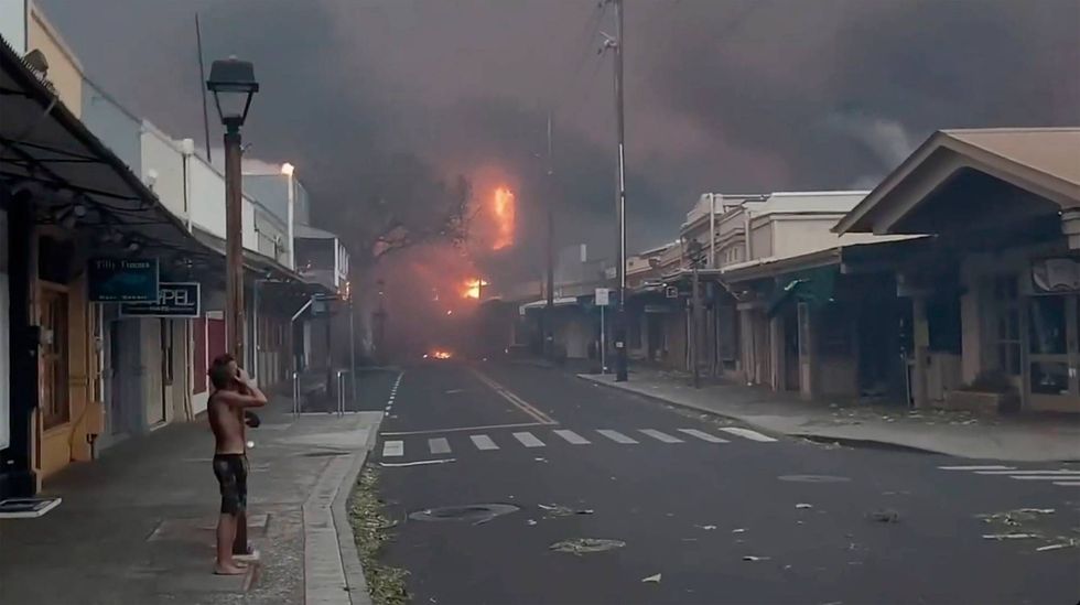 People watch as smoke and flames fill the air from raging wildfires on Front Street in downtown Lahaina, Maui on Tuesday, Aug. 8, 2023.
