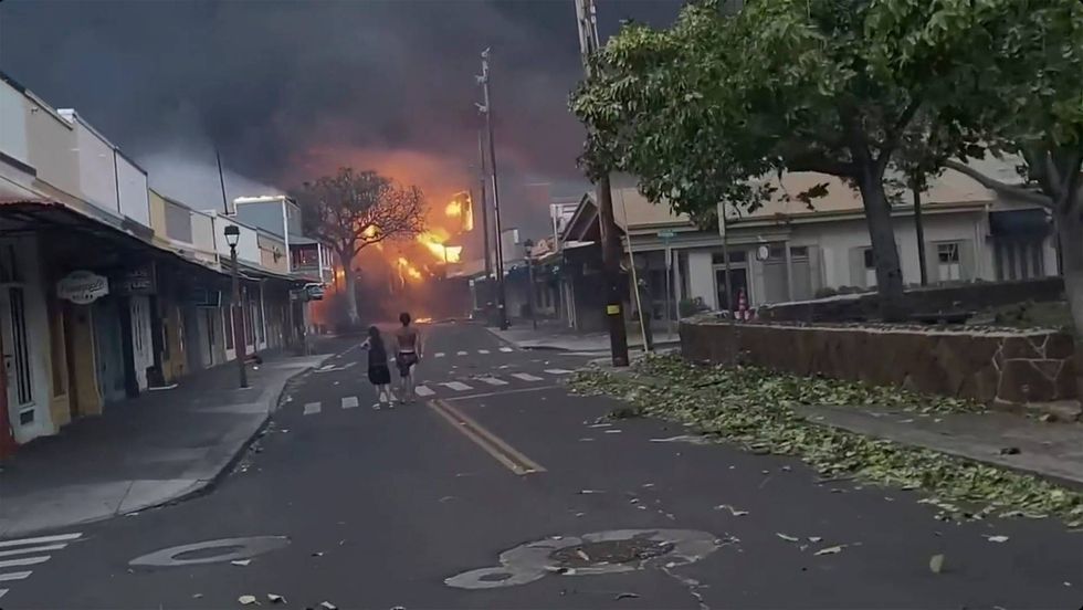 People watch as smoke and flames fill the air from raging wildfires on Front Street in downtown Lahaina, Maui on Tuesday, Aug. 8, 2023.