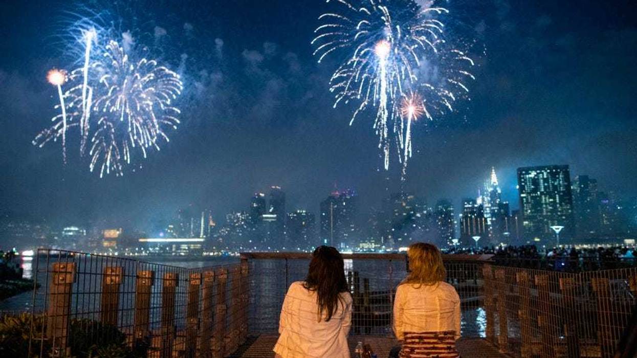 People watch fireworks lighting up the night sky over the East River from Hunter's Park South on July 04, 2021 in the Queens borough of New York City. This is the 45th annual display of the Macy's Independence Day fireworks show.