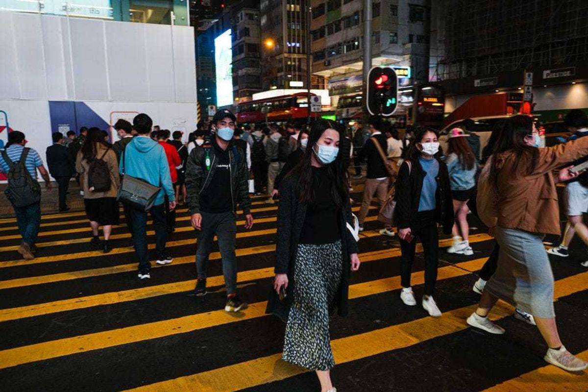 People wear protective masks and cross the street in Hong Kong December 9, 2020 in Hong Kong, China.