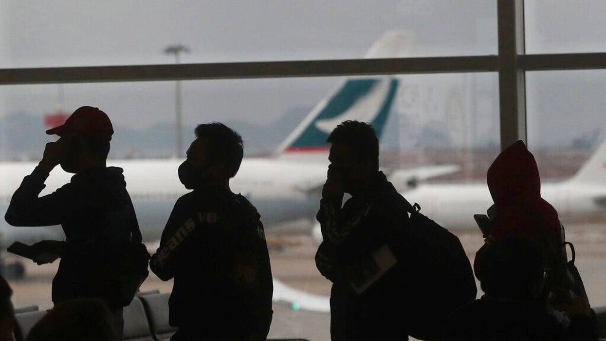 People wearing masks line up for departure at Hong Kong airport in Hong Kong, Tuesday, Feb. 4, 2020. Hong Kong on Tuesday reported its first death from a new virus, a man who had traveled from the mainland city of Wuhan that has been the epicenter of the
