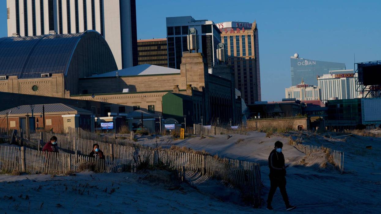 People wearing masks walk on the beach at dusk during the coronavirus pandemic on May 7, 2020 in Atlantic City, New Jersey.