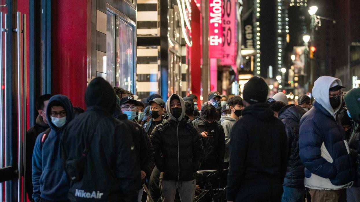 People wearing protective masks wait in line to enter Foot Locker store during Black Friday on November 27, 2020 in New York City.
