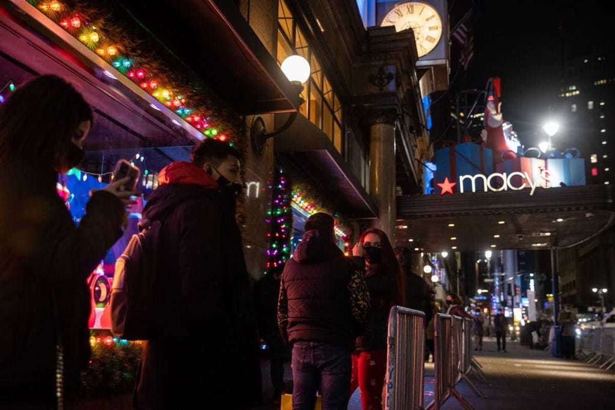 People wearing protective masks wait in line to enter Macy's store on November 27, 2020 in New York, United States.