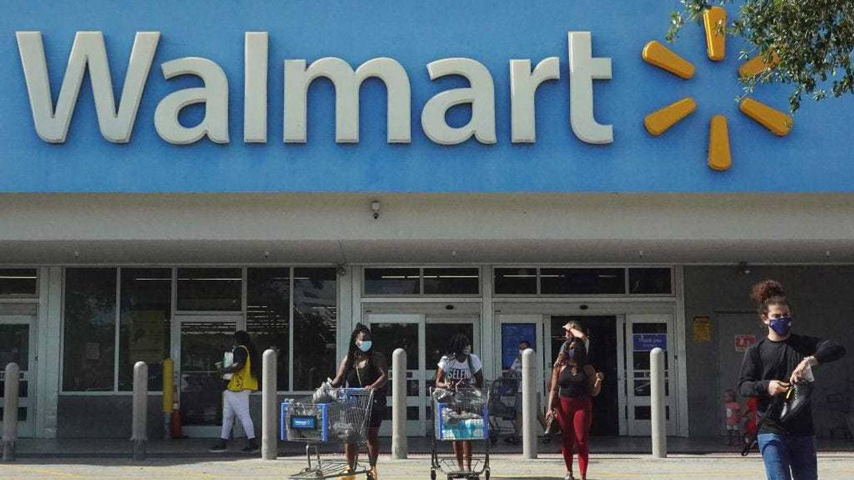 People wearing protective masks walk from a Walmart store.