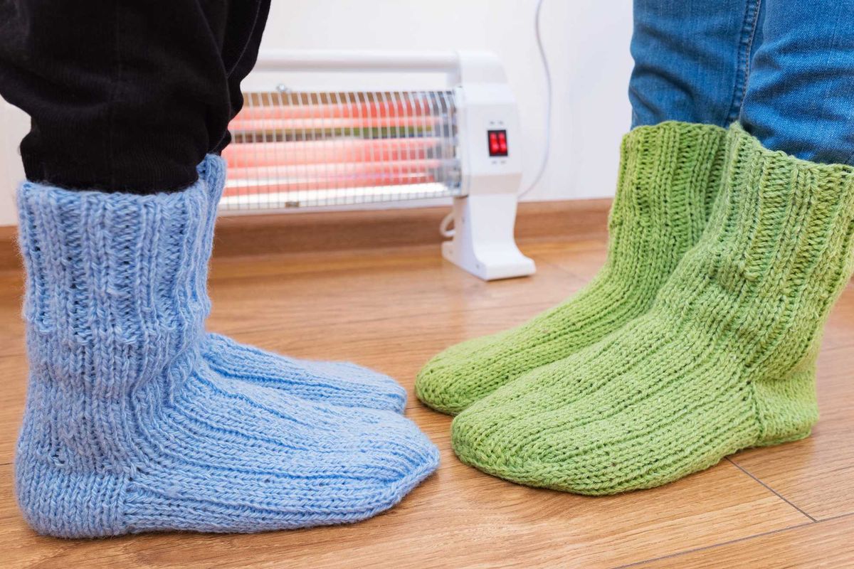 People wearing sock slippers in front of a space heater.