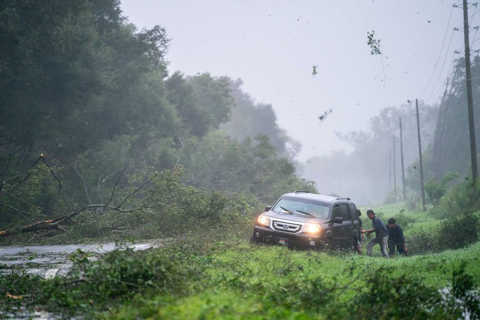 People work to free a vehicle stuck on the shoulder amid storm debris as Hurricane Idalia crosses the state on August 30, 2023 near Mayo, Florida