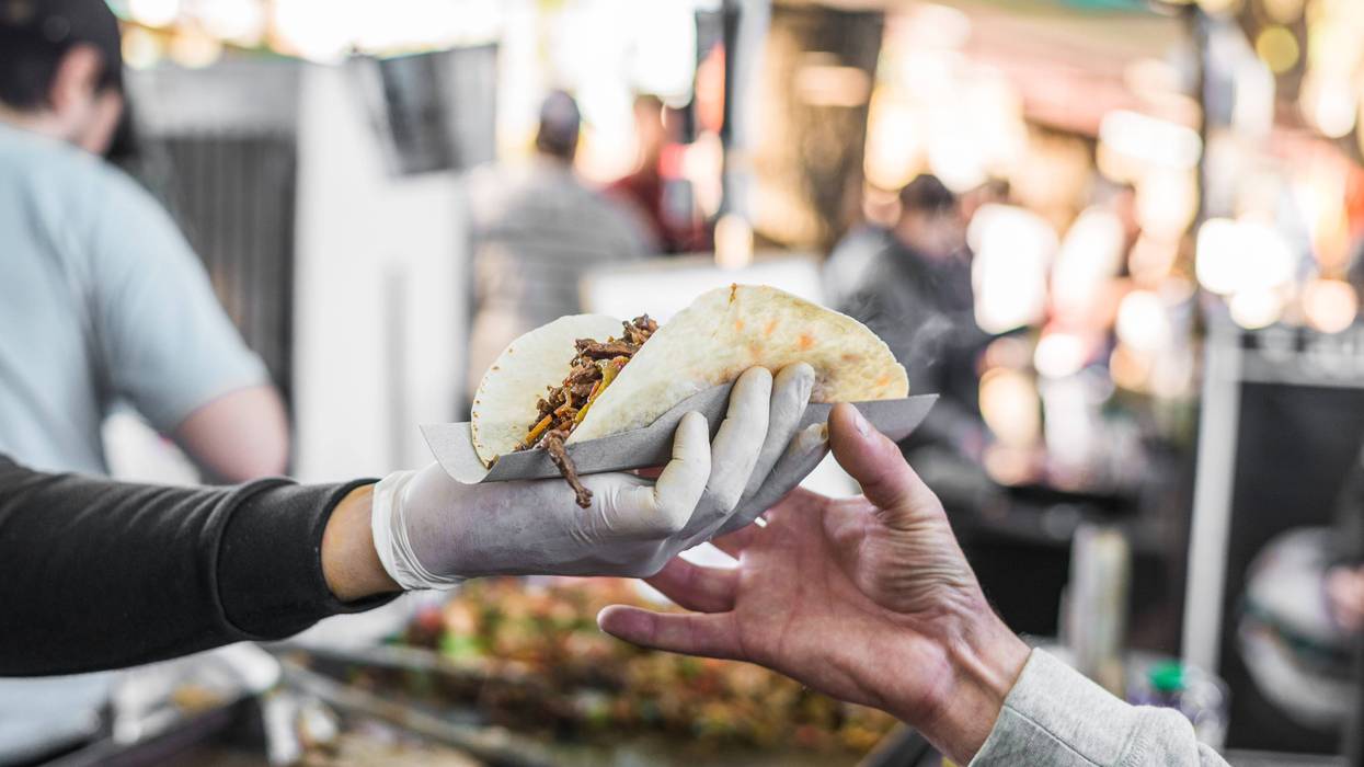 Person being handed a taco at an outdoor festival