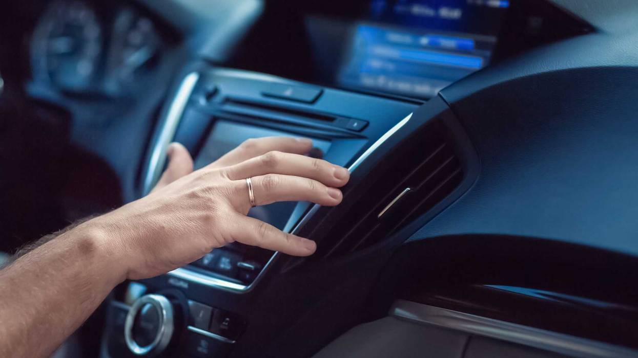Person changing radio dial in car