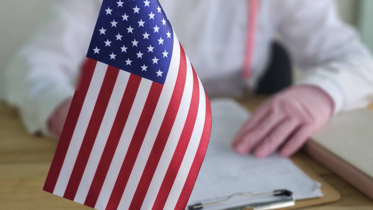 Person holding a document with a small American flag on a table during a focus task related to the USA concept