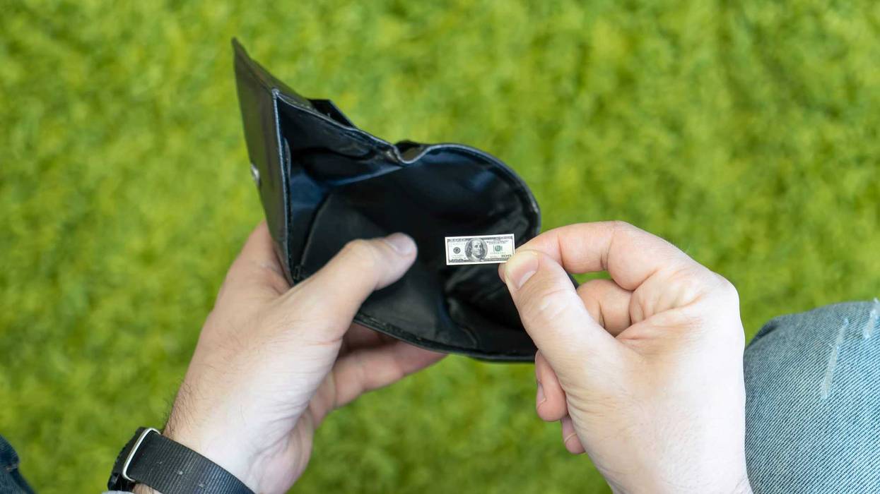 Person holding a dollar that is tiny in a wallet.