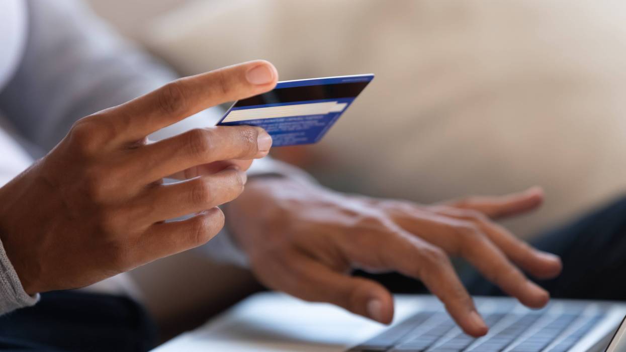 Person holds credit card while on a laptop
