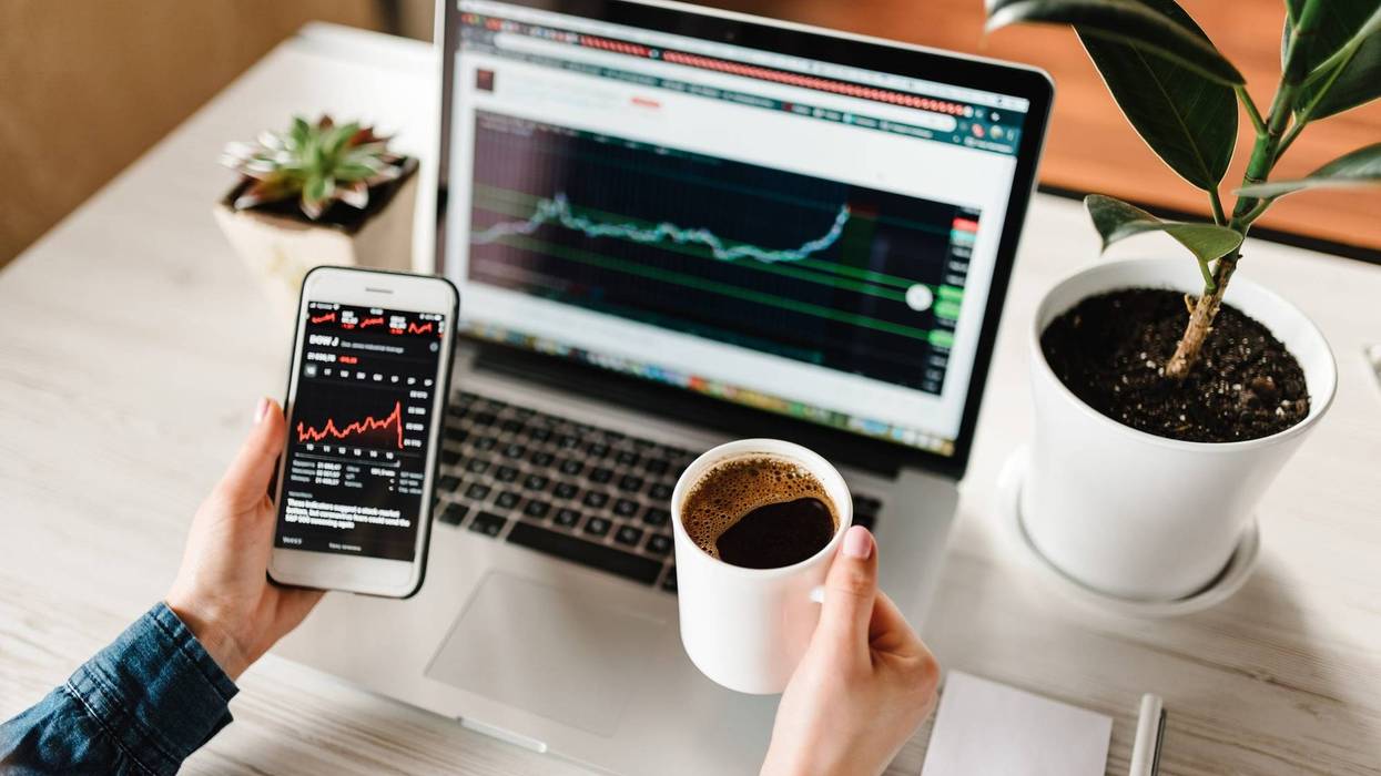 Person looking at investment information on laptop and mobile phone.