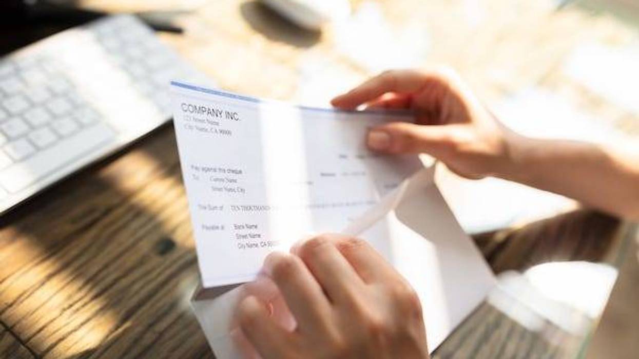 Person opening envelope with paycheck