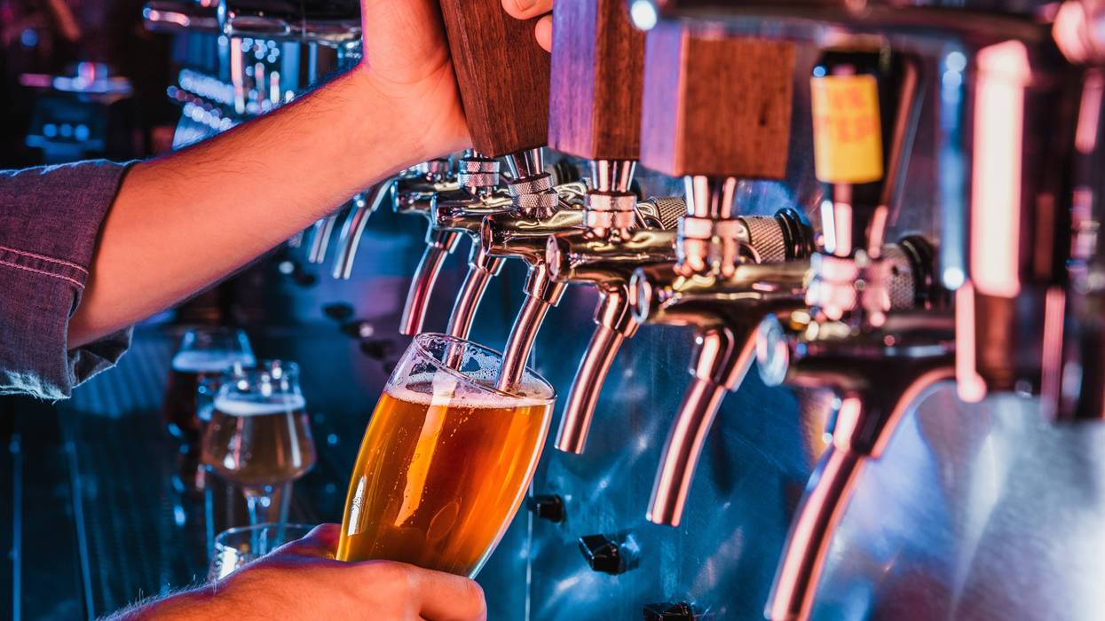 person pouring beer from tap