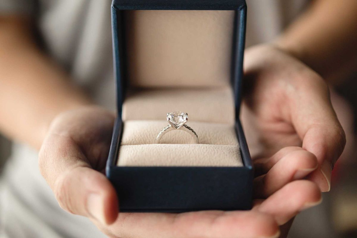 Person proposing with a diamond engagement ring.