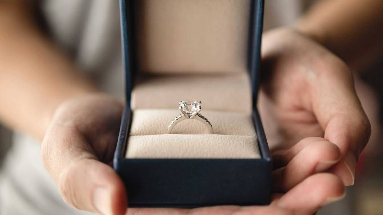 Person proposing with a diamond engagement ring.