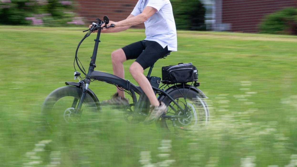 Person Riding a Folding Electric Bicycle with Motion Blur in an Urban Green Space
