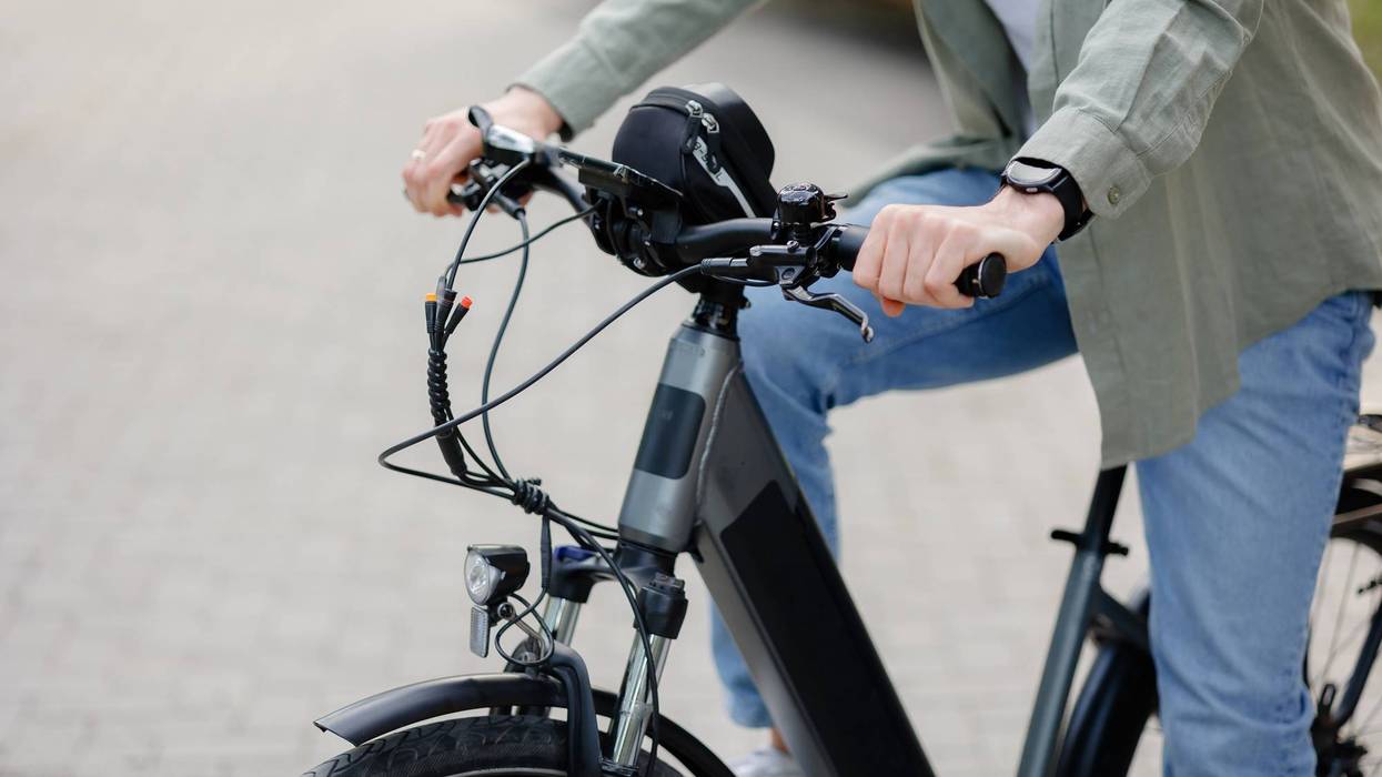 Person riding an electric bike on a brick pathway during daytime in a park setting