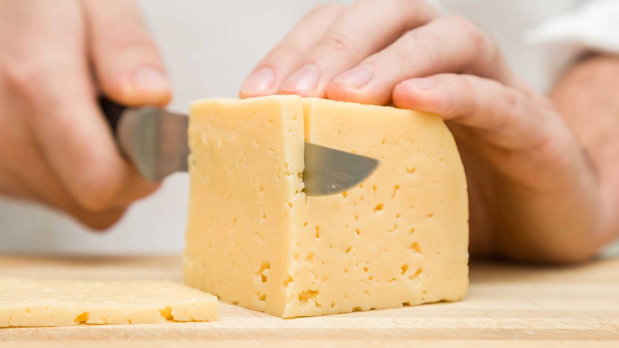Person slicing a block of cheese.