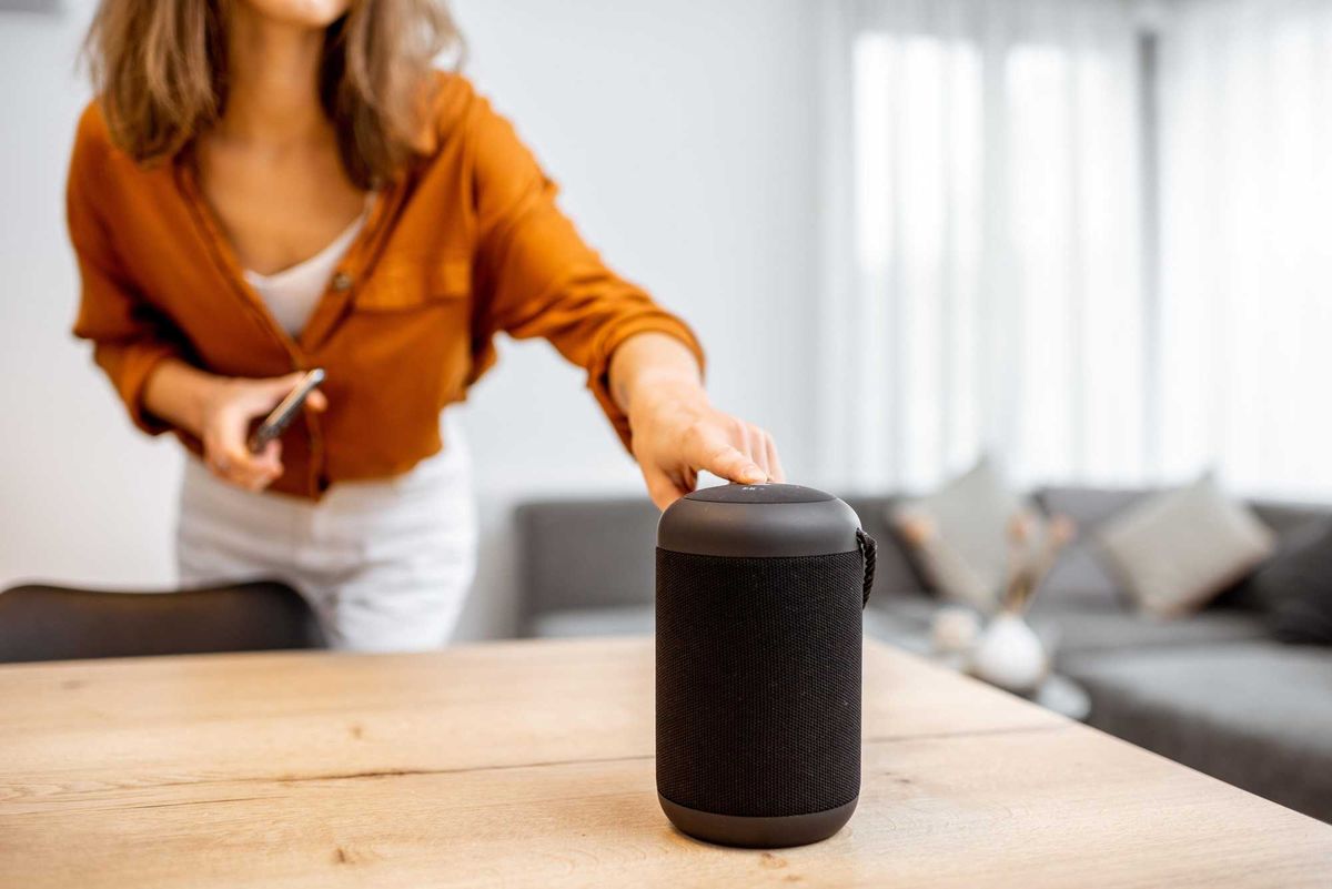 person turning on a smart speaker on a counter