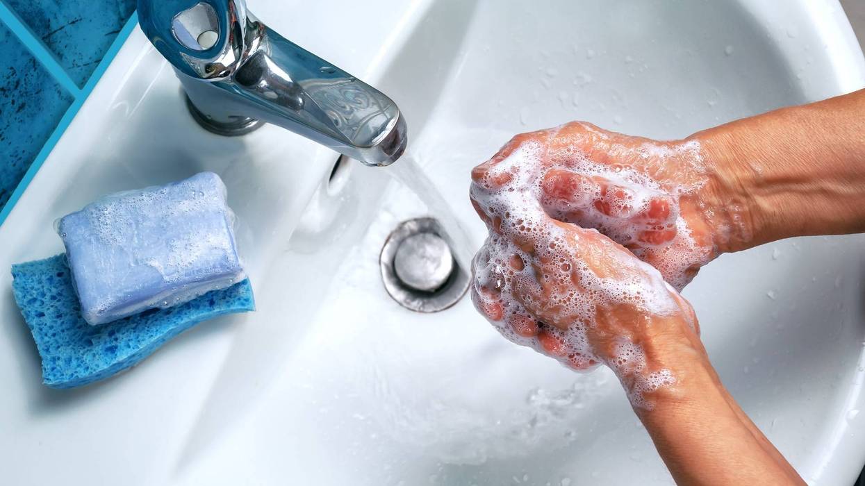 Person washing hands with soap and water in sink