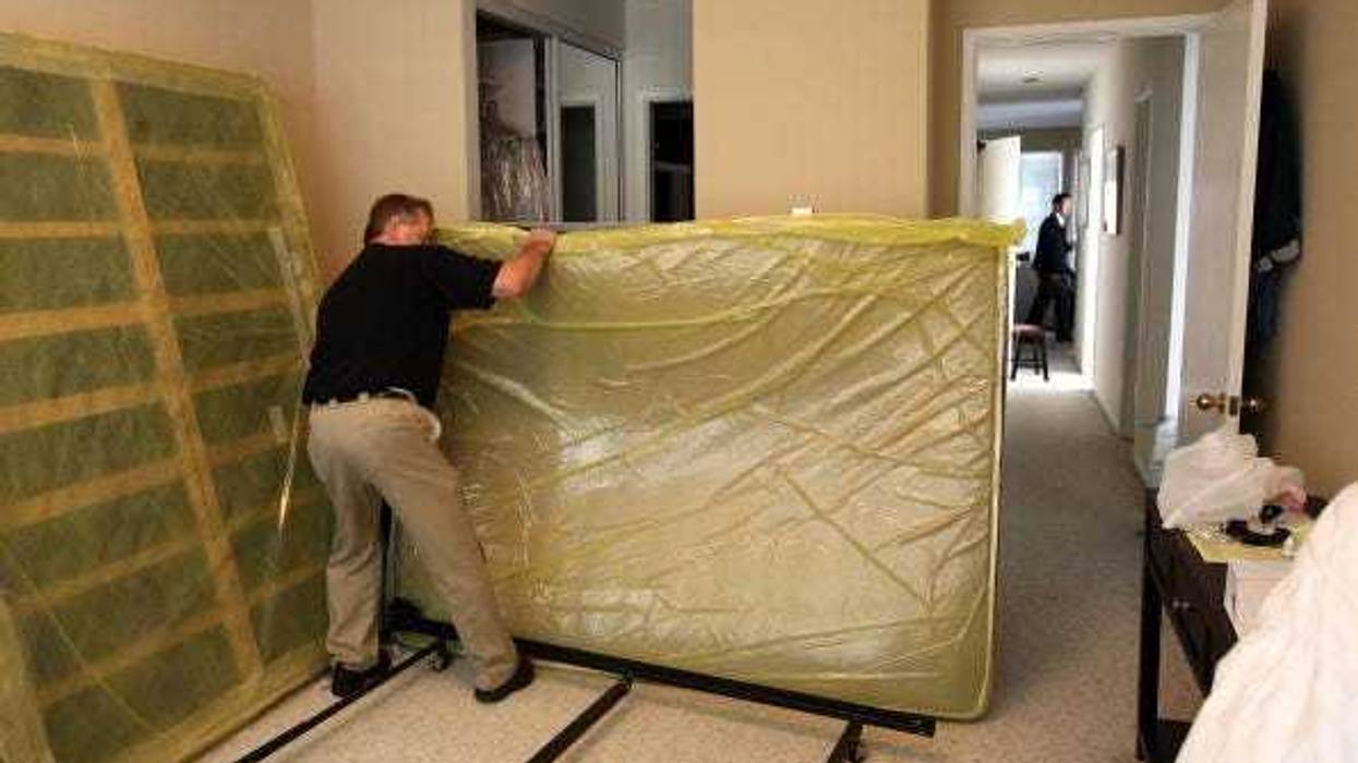 Pestec technician Darrell Azlin moves a bed as he preapares to use a heat treatment at an apartment with bed bug