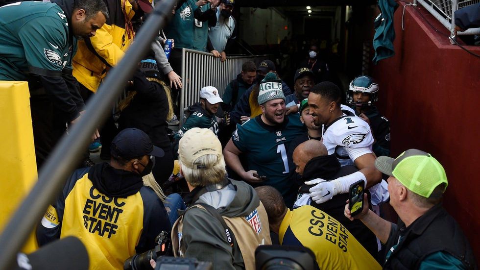 Philadelphia Eagles quarterback Jalen Hurts interacts with fans who fell onto the ground after a railing collapsed at FedExField on Jan. 2, 2022, in Landover, Maryland.