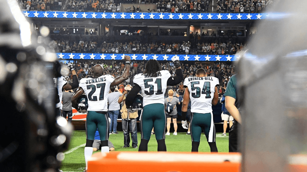 Philadelphia Eagles strong safety Malcolm Jenkins (27) and defensive end Steven Means (51) raise their right hands up during the playing of the national anthem prior to the game against the Chicago Bears at Soldier Field.