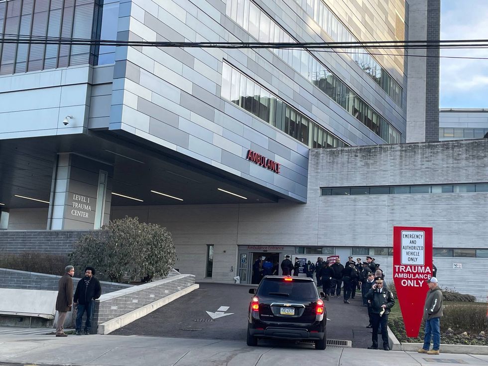 Philadelphia law enforcement officials wait outside Penn Presbyterian Medical Center for more details about the office who was shot on Wednesday.