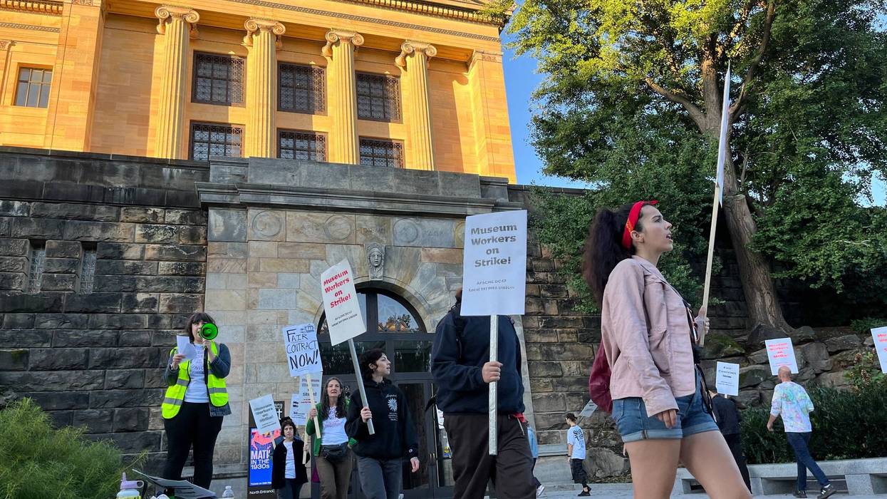 Philadelphia Museum of Art employees hold picket signs in front of a museum entrance.