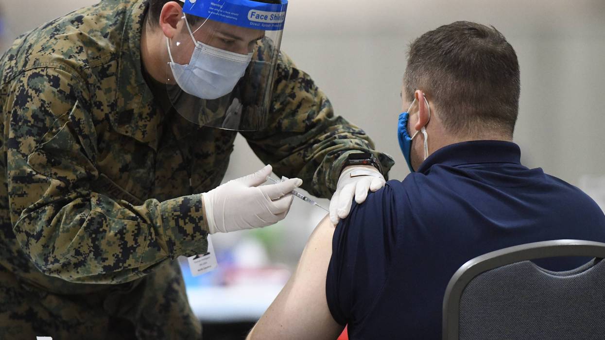 PHILADELPHIA, PA - MARCH 02: A member of the U.S. Armed Forces administers a COVID-19 vaccine to a police officer at a FEMA community vaccination center on March 2, 2021 in Philadelphia, Pennsylvania. Located at the Pennsylvania Convention Center, the site is being run as a partnership between the city and the federal government. It is part of a nearly $4 billion plan for FEMA to support more than 400 community vaccination centers across the country.