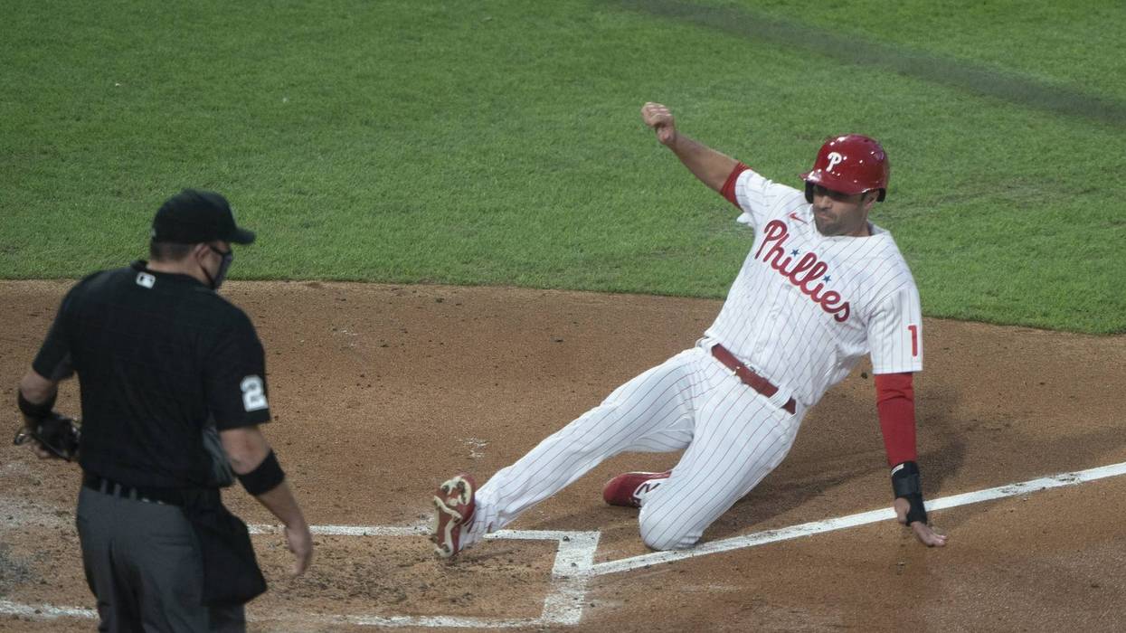 Philadelphia Phillies first baseman Neil Walker (12) slides safely into home plate on Philadelphia Phillies catcher Andrew Knapp (15) (not pictured) RBI single during the second inning against the New York Yankees at Citizens Bank Park.