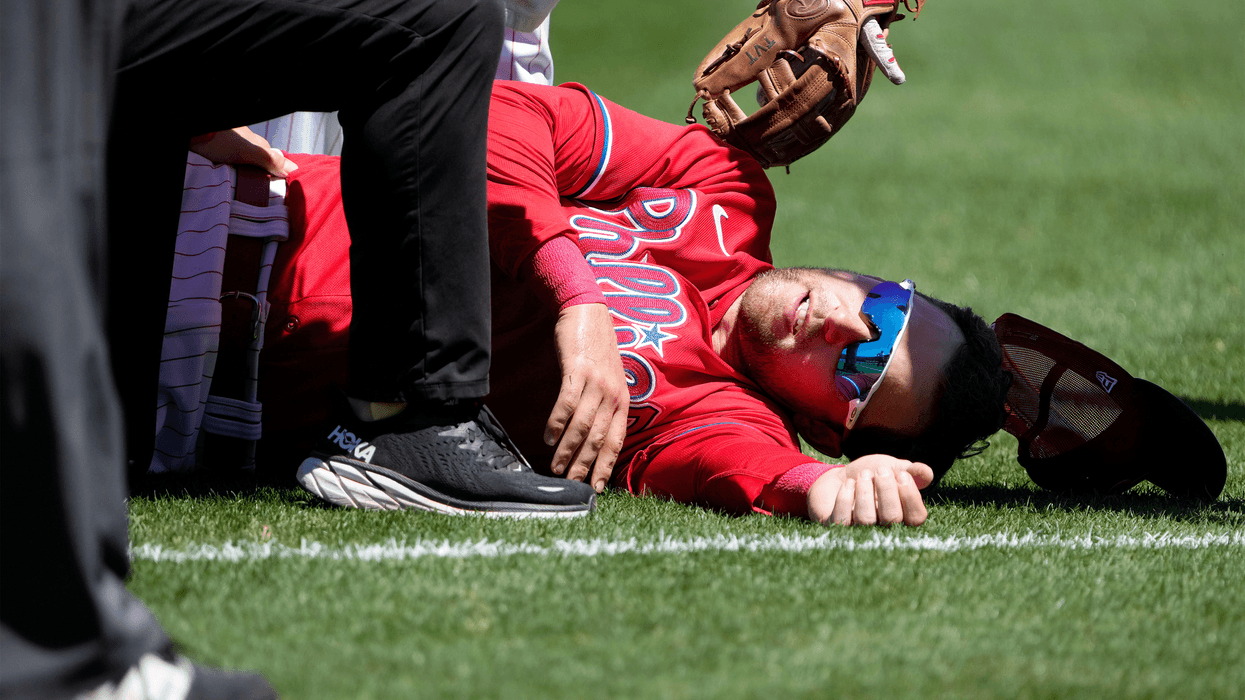 Phillies first baseman Rhys Hoskins lying on the field of Baycare Ballpark in Clearwater Florida. He was injured Thursday attempting to field a ball and subsequently was carted off the field for an MRI exam.