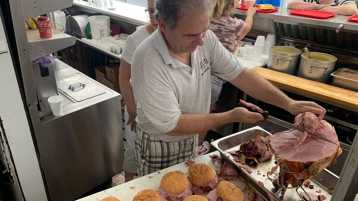 Photo of Harry Lile, Owner of Lile's Ham Shop, cutting ham during the closing day of the community staple restaurant