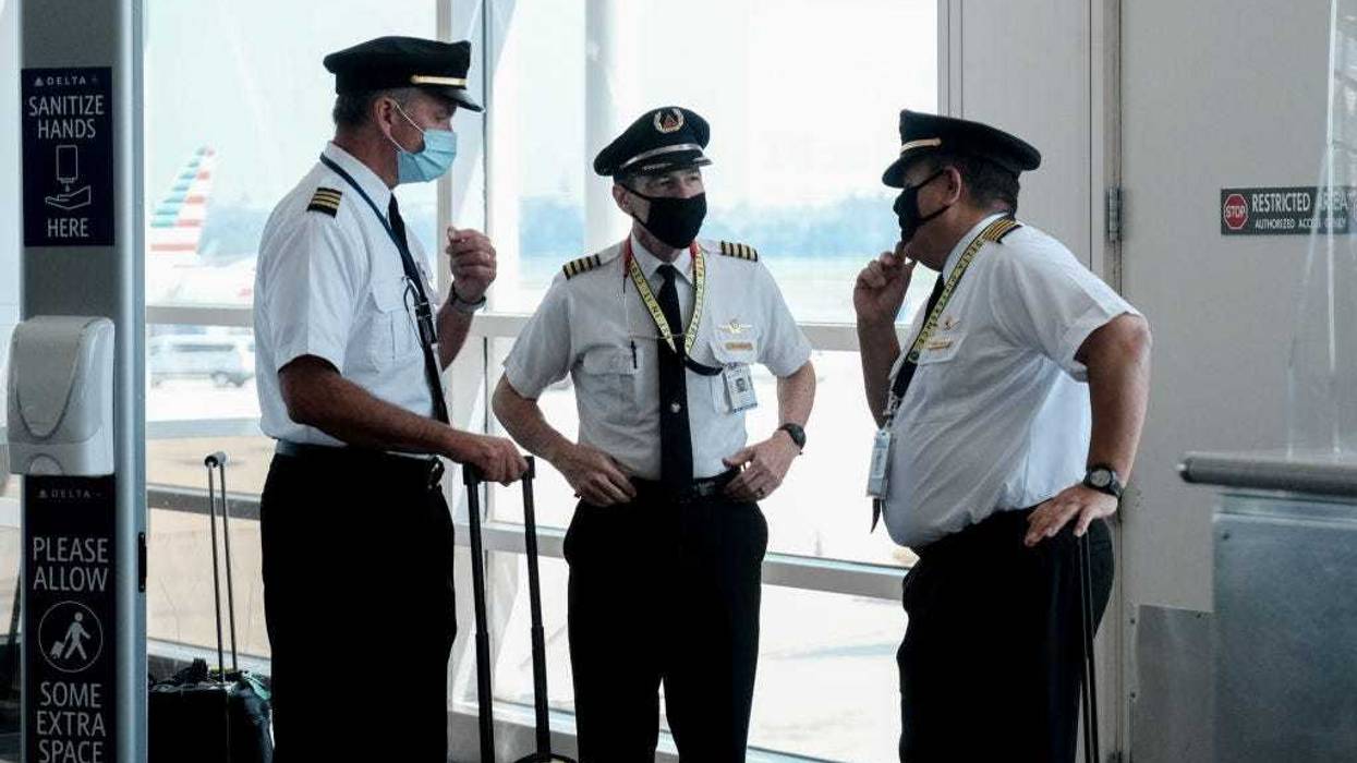Pilots talk after exiting a Delta Airlines flight at the Ronald Reagan National Airport on July 22, 2020 in Arlington, Virginia. During the COVID-19 pandemic, all employees and passengers are required to wear facemasks while onboard a Delta plane. (Photo by Michael A. McCoy/Getty Images)