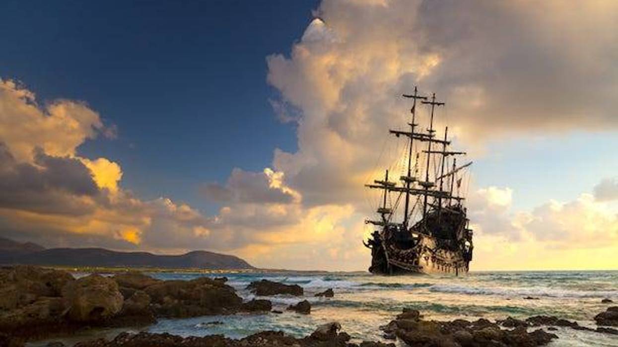 Pirate ship at the open sea at the sunset