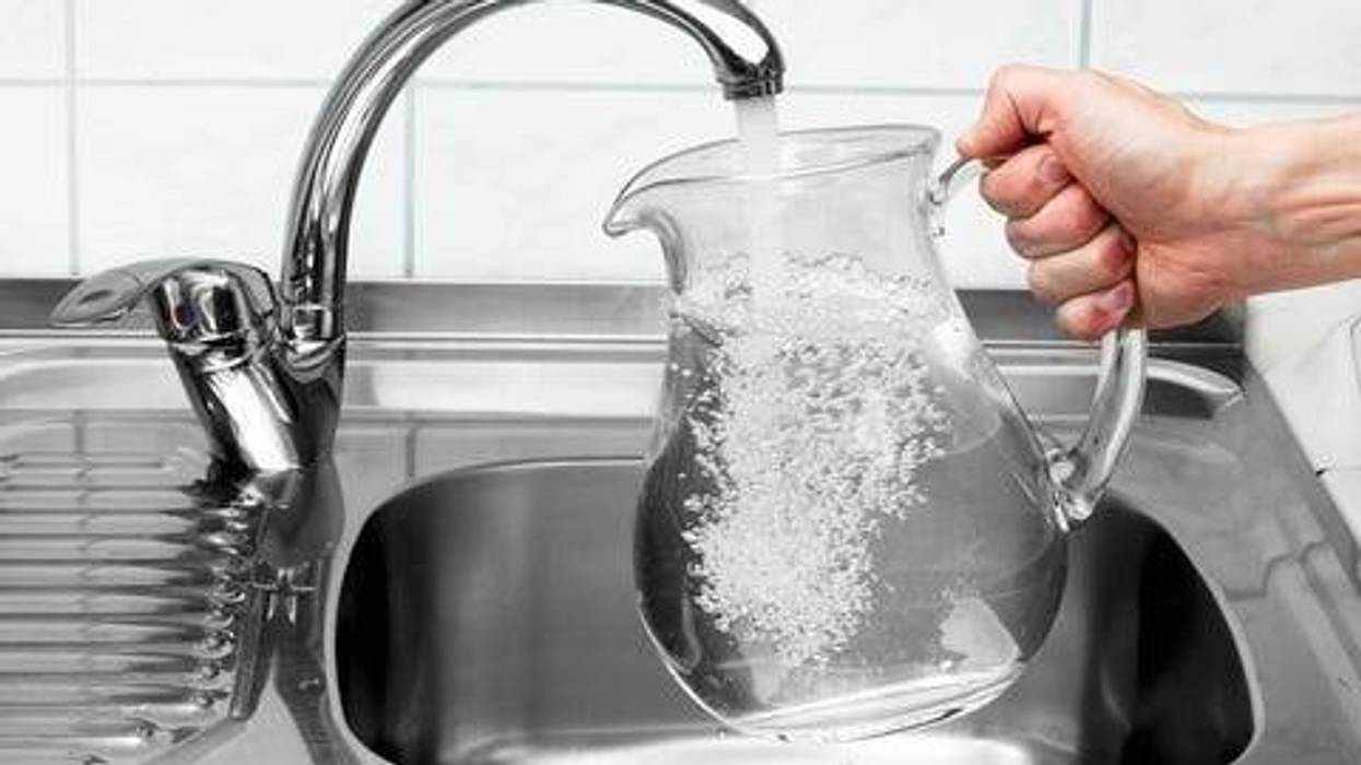 Pitcher being filled with drinking water from kitchen faucet.