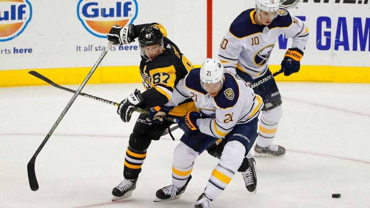 Pittsburgh Penguins' Sidney Crosby (87) and Buffalo Sabres' Kyle Okposo (21) tangle as they try to control the puck in front of Henri Jokiharju (10) during the first period of an NHL preseason hockey game, Saturday, Sept. 28, 2019, in Pittsburgh.