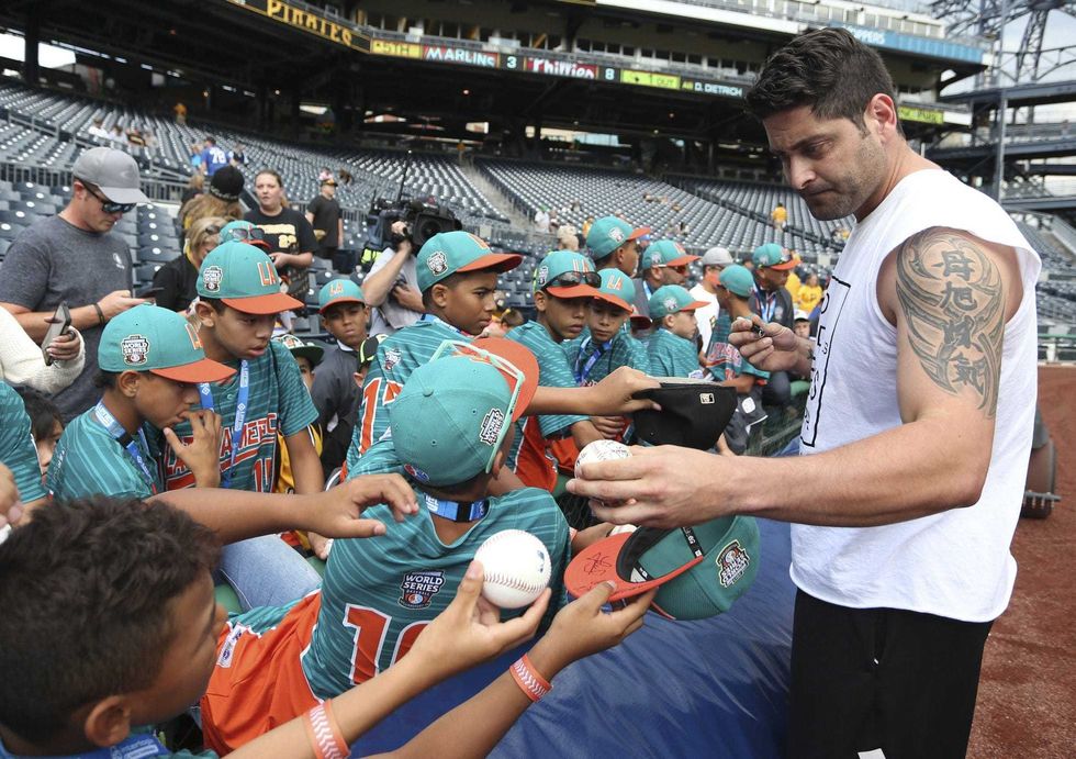 Pittsburgh Pirates catcher Francisco Cervelli (right) signs autographs for the team that represented Latin America in the Little League World Series