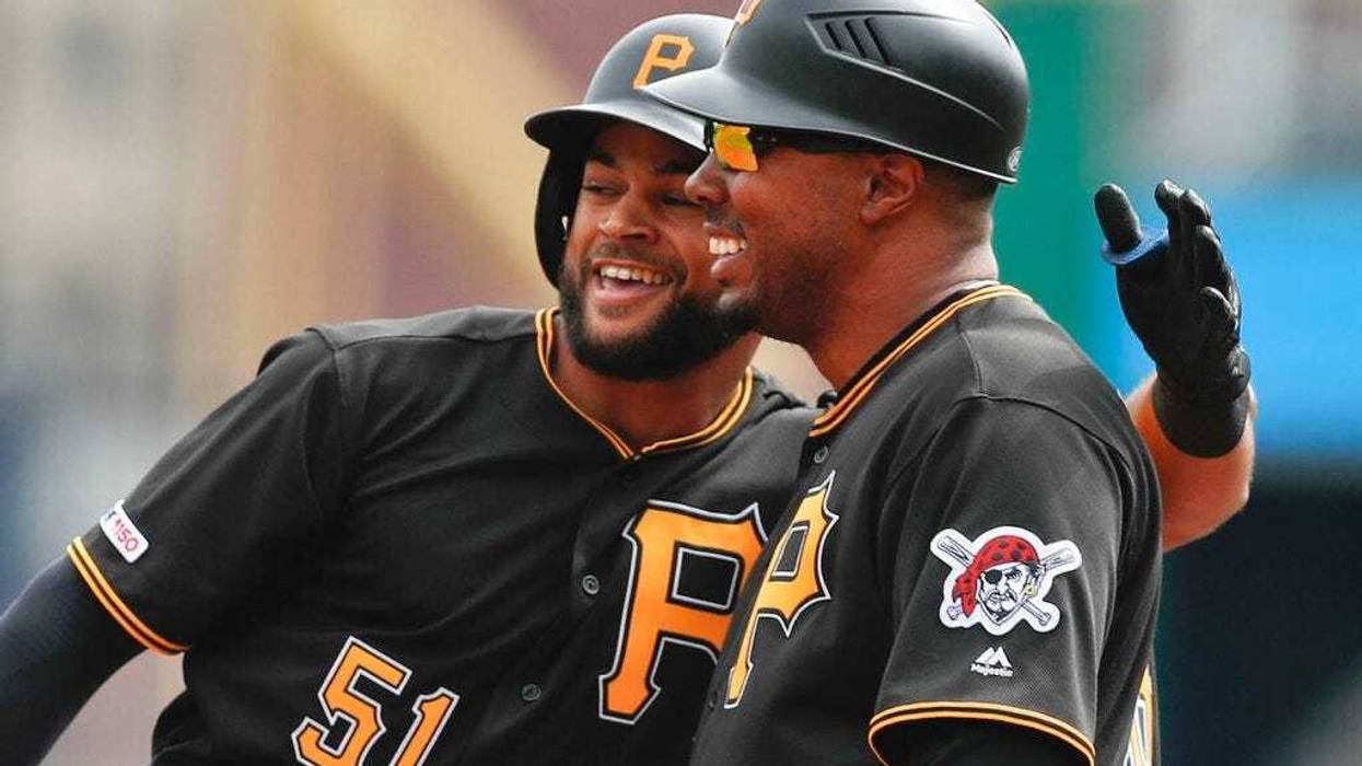 Pittsburgh Pirates Jason Martin, left, puts his arm around first base coach Kimera Bartee after getting his first major league hit off Cincinnati Reds starting pitcher Tanner Roark in the first inning of a baseball game, Saturday, April 6, 2019, in Pittsb