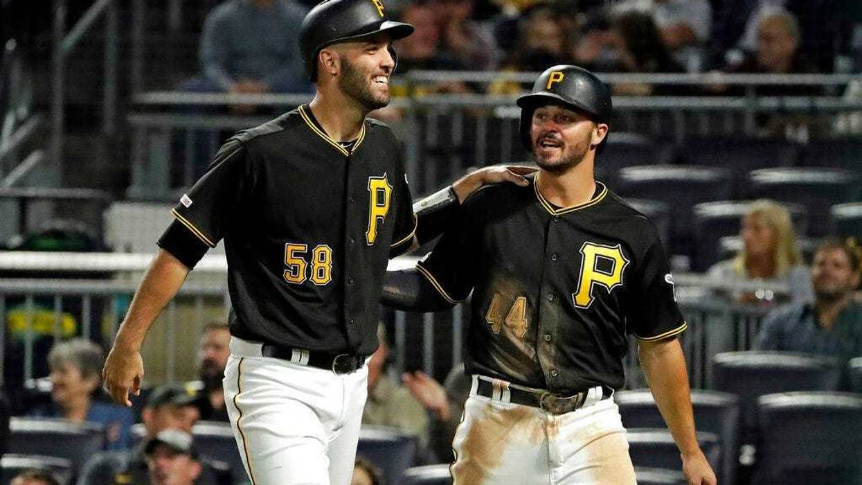 Pittsburgh Pirates' Kevin Kramer (44) and Jacob Stallings return to the dugout after scoring on a single by Erik Gonzalez off Chicago Cubs starting pitcher Kyle Hendricks during the seventh inning of a baseball game in Pittsburgh, Tuesday, Sept. 24, 2019.