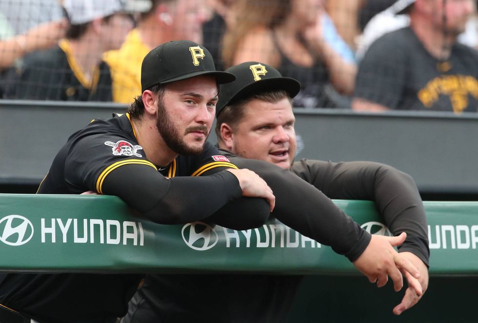Pittsburgh Pirates starting pitcher Paul Skenes (left) and coach Daniel Vogelbach (right) look on from the dugout against the St. Louis Cardinals during the sixth inning at PNC Park.