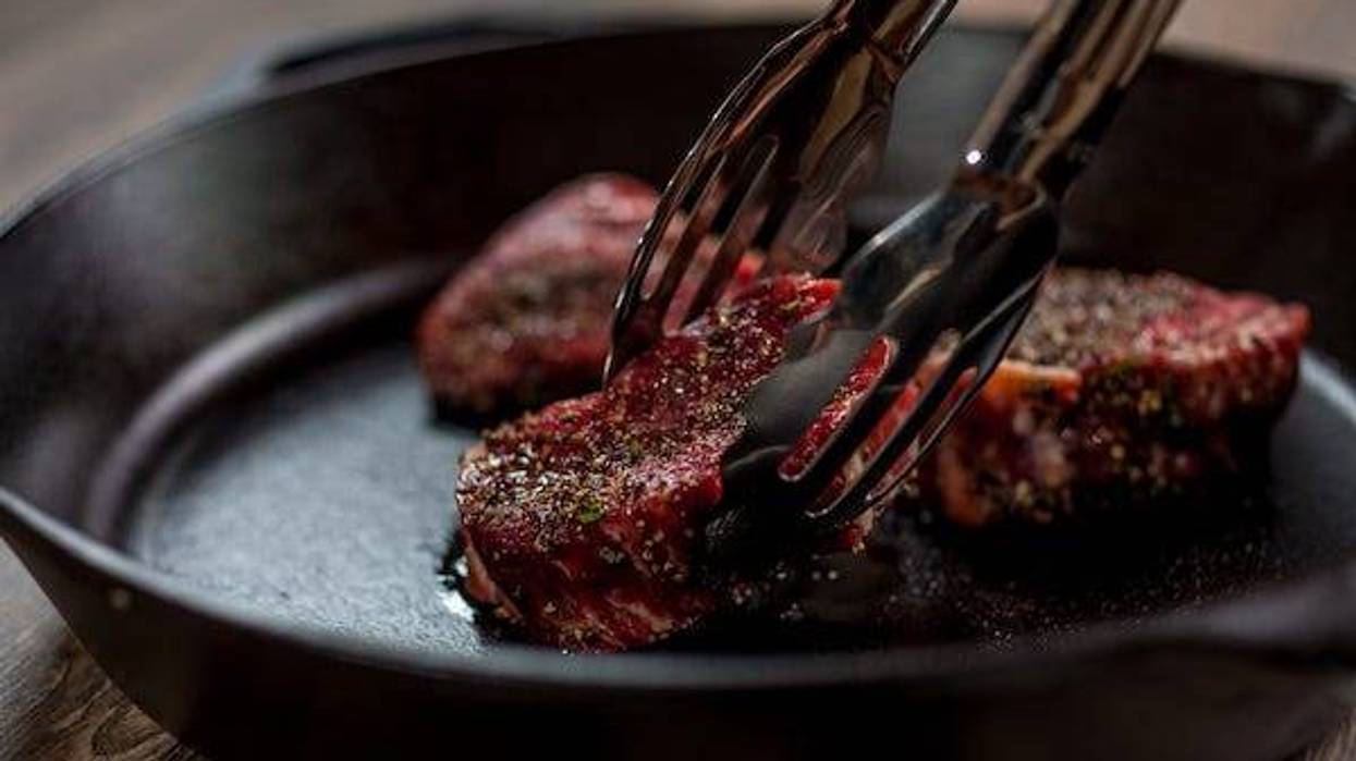 Placing steaks on a pan with tongs