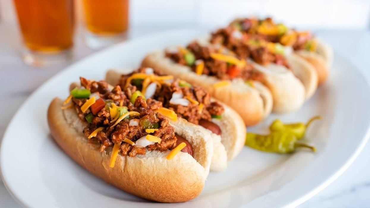 plate of chili dogs with glasses of beer in background