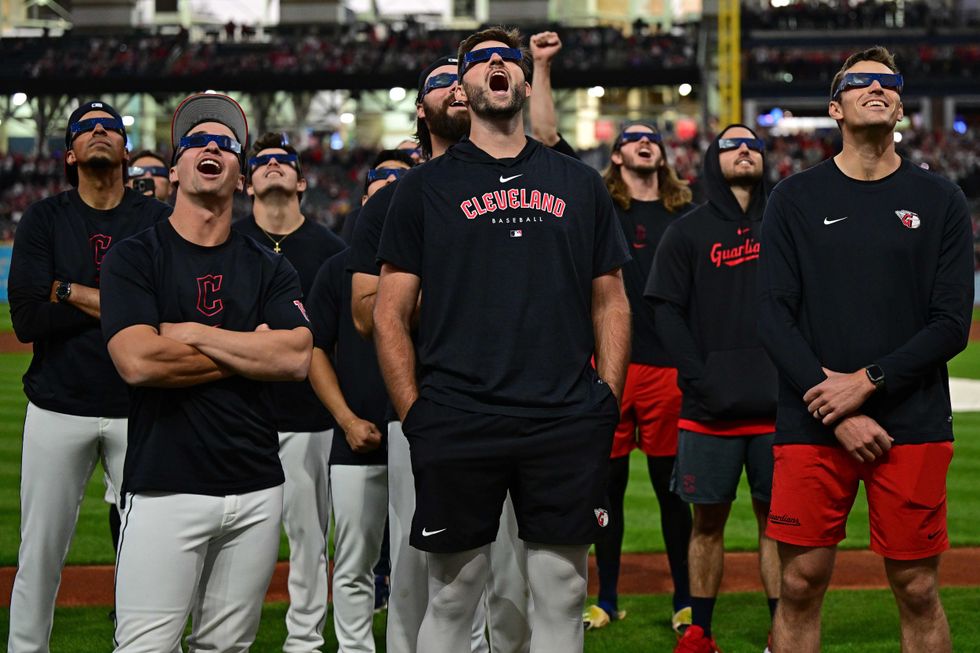Players for the Cleveland Guardians watch a total solar eclipse before a game against the Chicago White Sox at Progressive Field.
