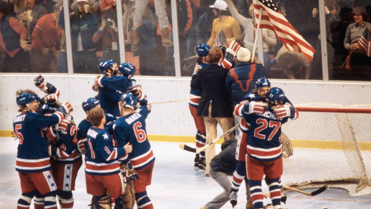Players from the United States Ice Hockey team celebrate and wave the Stars and Stripes flag after defeating Team Finland to win the gold medal during the Men's Ice Hockey Final game on 24th February 1980 during the XIII Olympic Winter Games at the Olympic Fieldhouse Olympic Arena in Lake Placid, New York, United States.