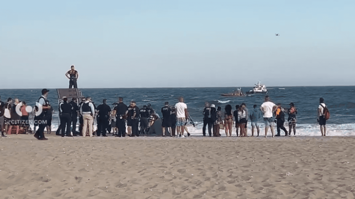 Police and beachgoers observe official sea vessels searching for two missing teen swimmers at Jacob Riis Park in Queens on Friday.